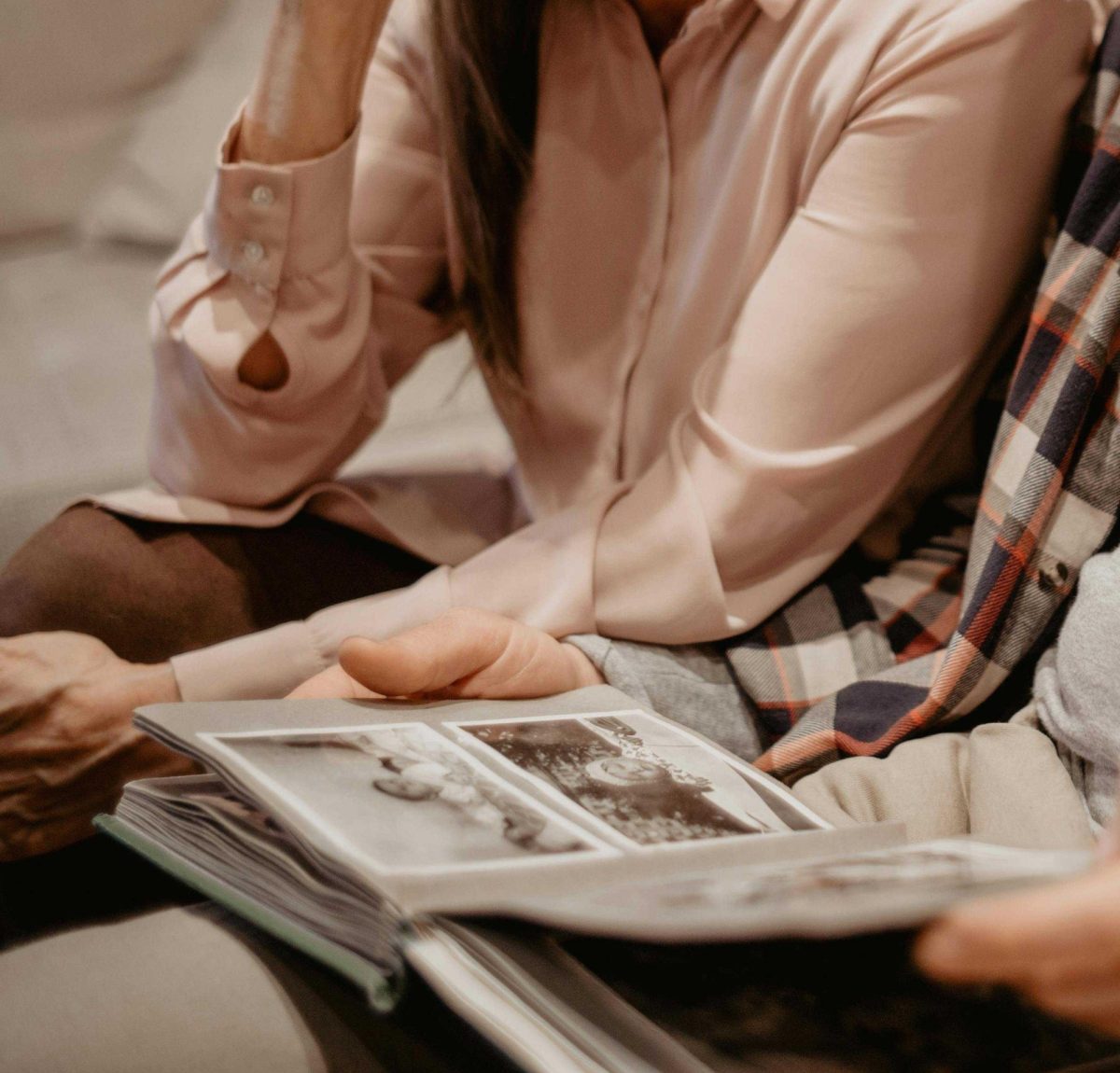 Two people sit side by side and look at a photo album