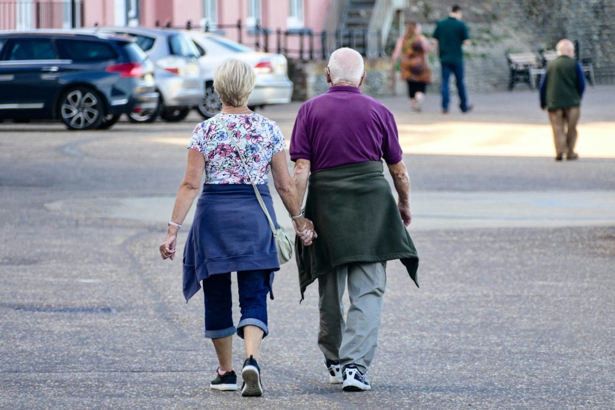 An older couple is seen walking holding hands