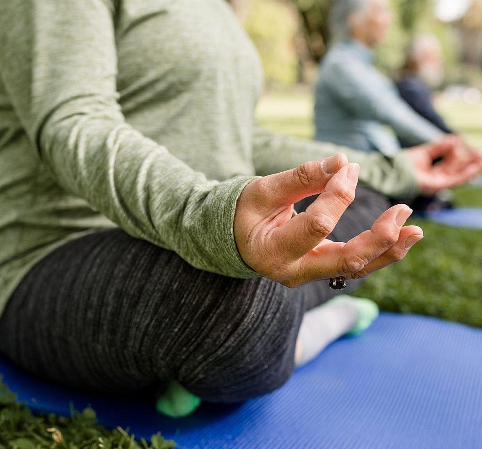 Woman seated on mat doing yoga close up of hand